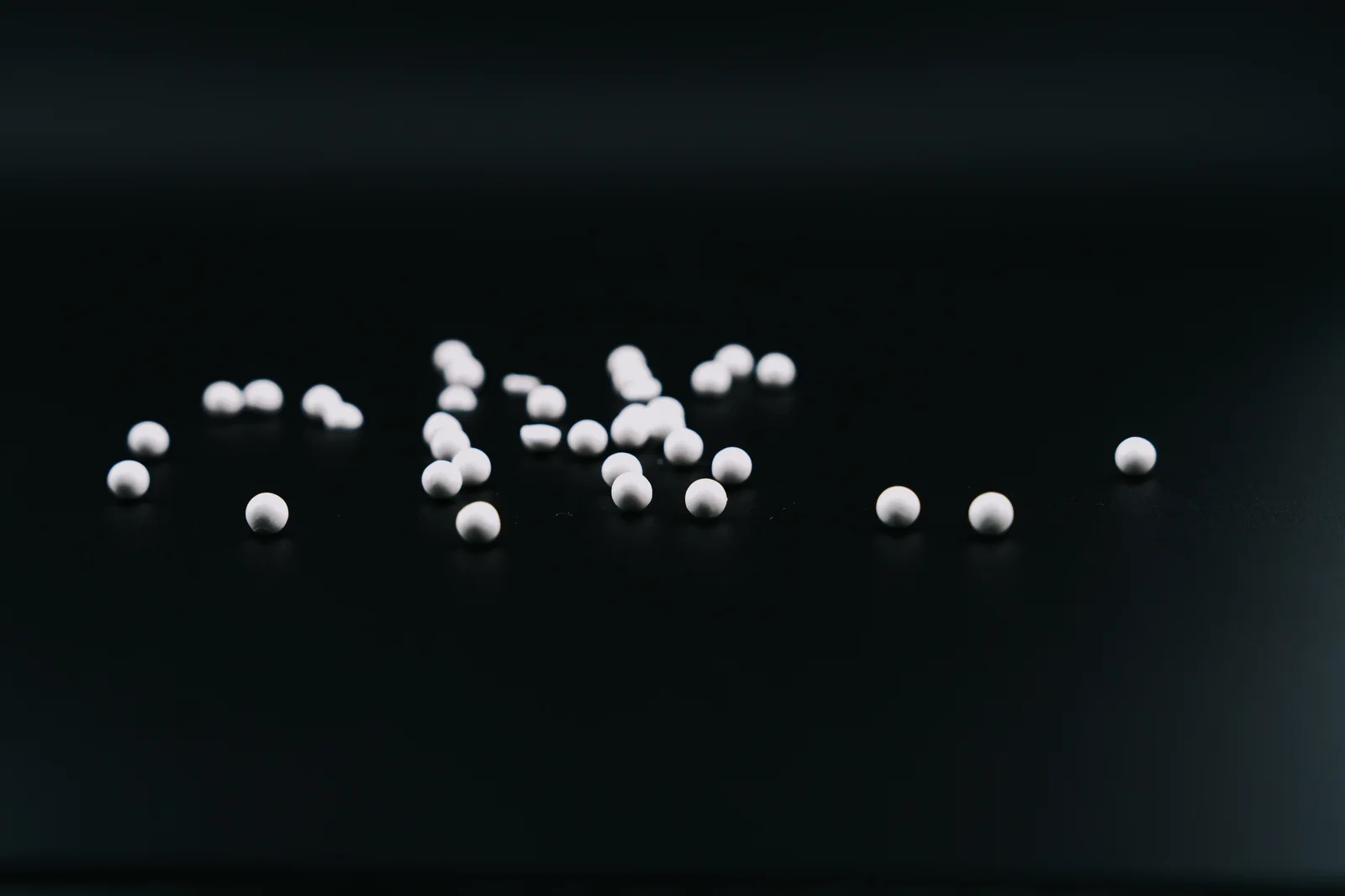 White lyophilized beads photographed on a dark studio surface.
